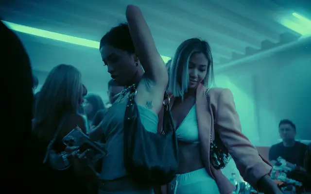 Friends dancing under teal club lighting