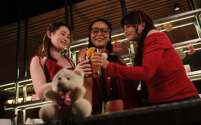 Three friends toasting cocktails at a bar