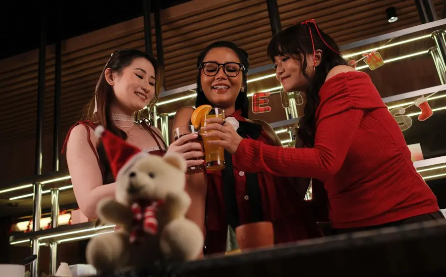 Three friends toasting cocktails at a bar
