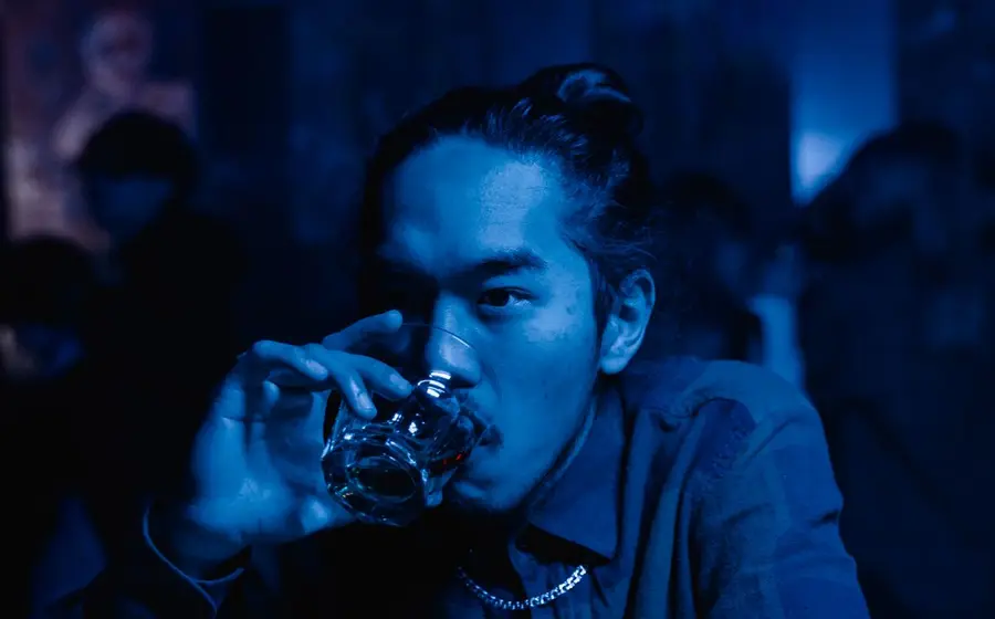 Man with a whisky glass in a blue-lit club